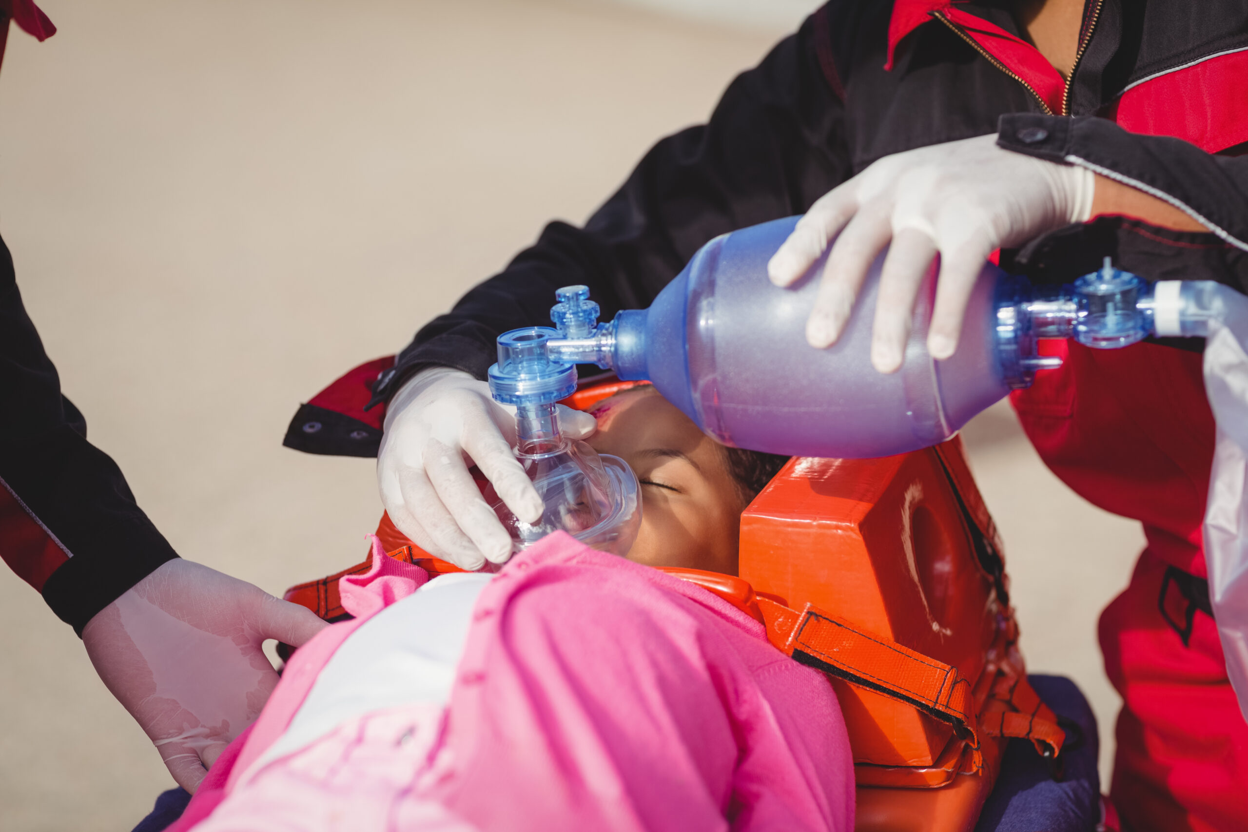 Paramedic giving oxygen to injured girl at accident spot